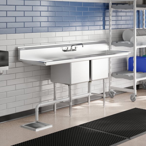 A Regency stainless steel two compartment sink with drainboards on a counter.