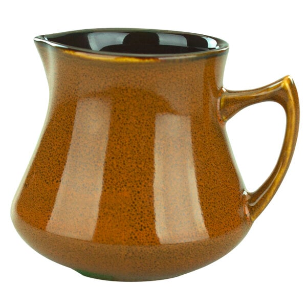 A brown pitcher with a black handle.