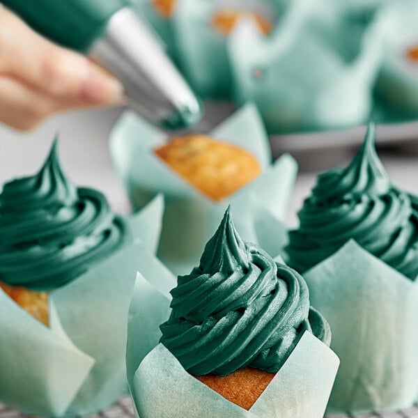 A close up of a cupcake with green frosting swirled on top.