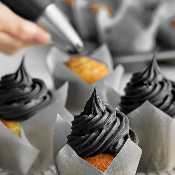 Black frosting piped onto a cupcake using a pastry bag.