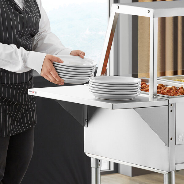 A person in a black apron using a ServIt solid tray slide to hold a stack of plates.