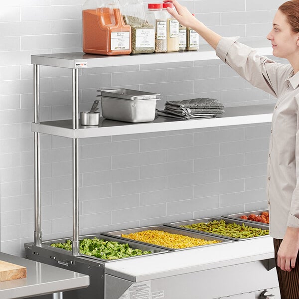 A woman standing in front of a metal shelf with food on it.