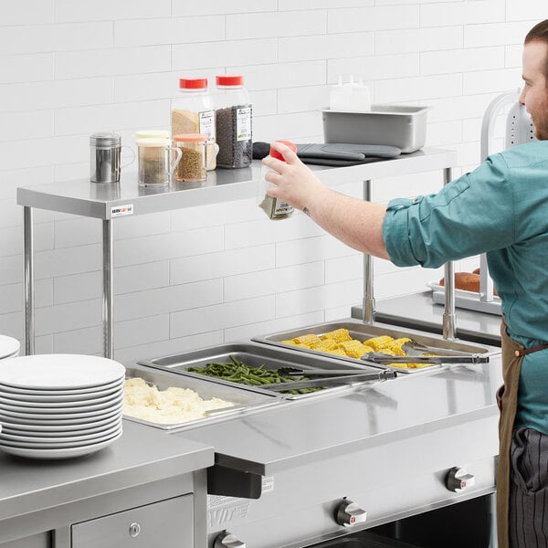 A man installing a ServIt single overshelf on a steam table.