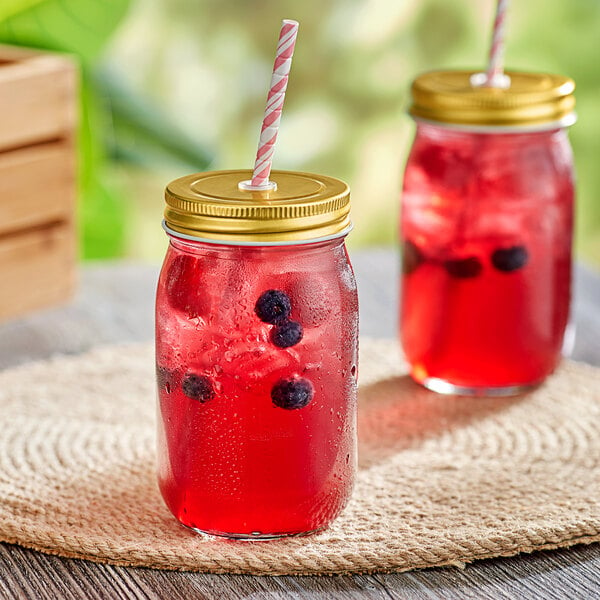 Two Acopa Rustic Charm drinking jars with red liquid and straws on a table, one with blueberries.