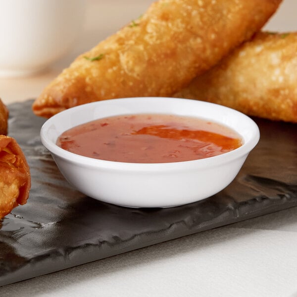 A plate of fried spring rolls with dipping sauce served in a white American Metalcraft Jane Collection sauce cup.