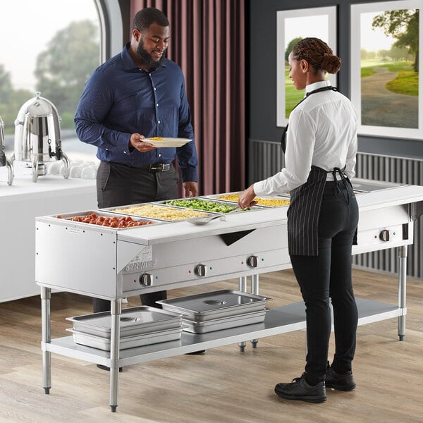 A man and woman using a ServIt electric steam table to fill their plates.