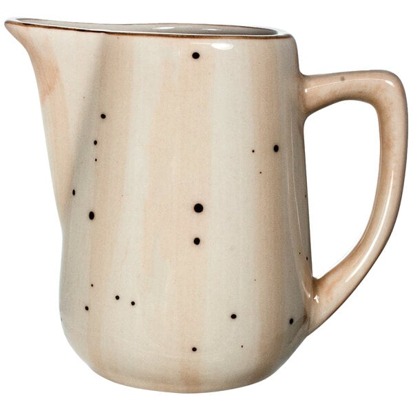 A white Rotana porcelain creamer with black dots.