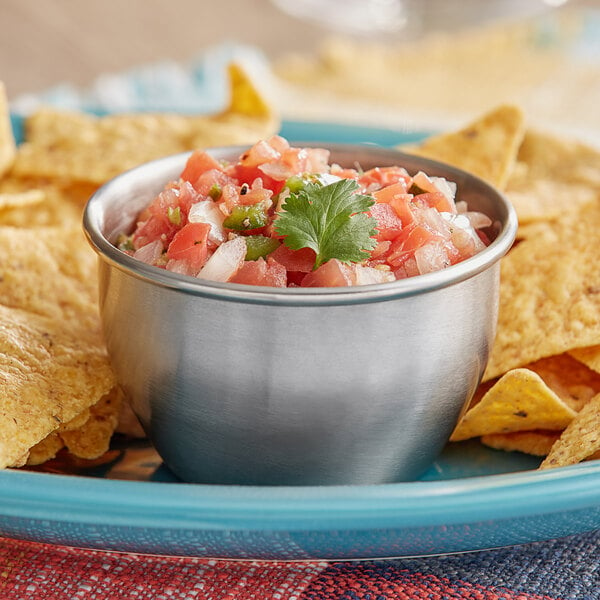 An American Metalcraft stainless steel round sauce cup filled with salsa and tortilla chips on a table in a Mexican restaurant.