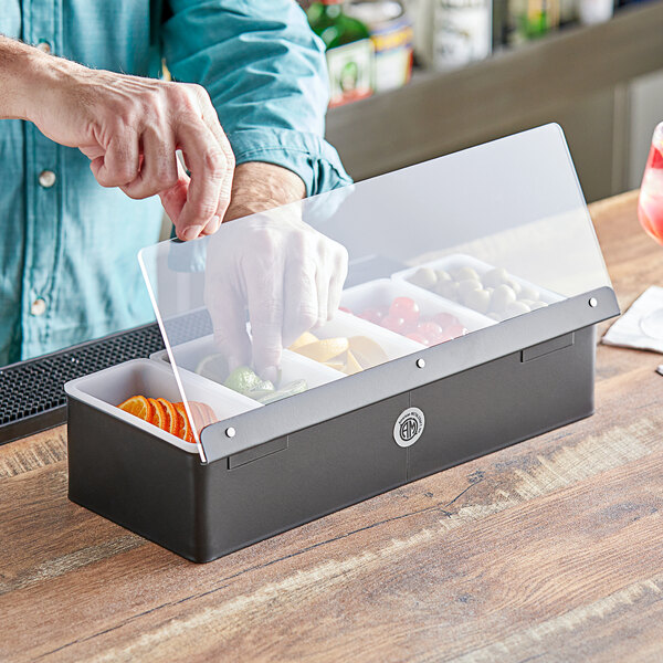 A person putting vegetables into an American Metalcraft matte black condiment container on a counter.