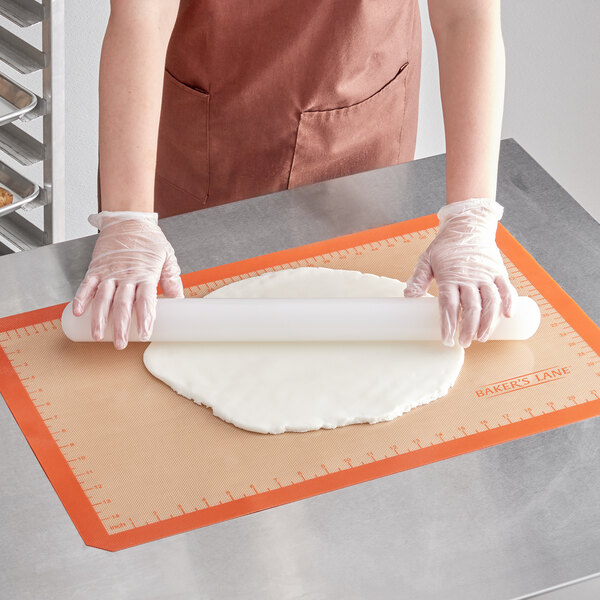 A woman rolling out dough on a Baker's Lane silicone baking mat.
