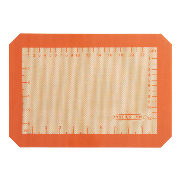 An orange Baker's Lane silicone baking mat with ruler indices.