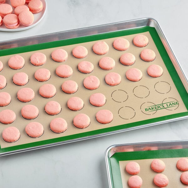 Two Baker's Lane heavy-duty green silicone baking mats with pink macarons on them.