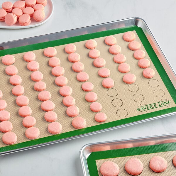 A Baker's Lane heavy-duty green silicone baking mat with pink macarons on it.