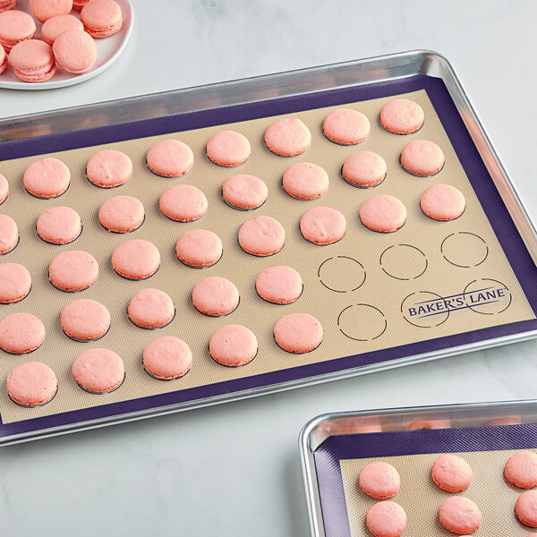 Two Baker's Lane purple silicone baking mats with pink macarons on them.