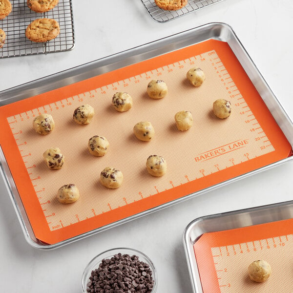 A Baker's Lane baking sheet with cookies on a baking mat.