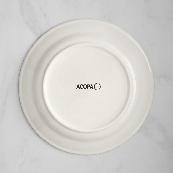An Acopa ivory stoneware plate with blue bands and black text on the rim.