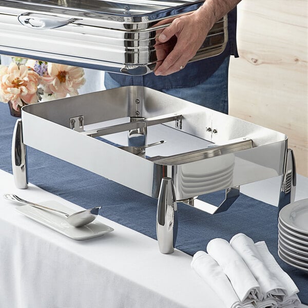 A person holding a metal container on a silver tray with a plate on it.
