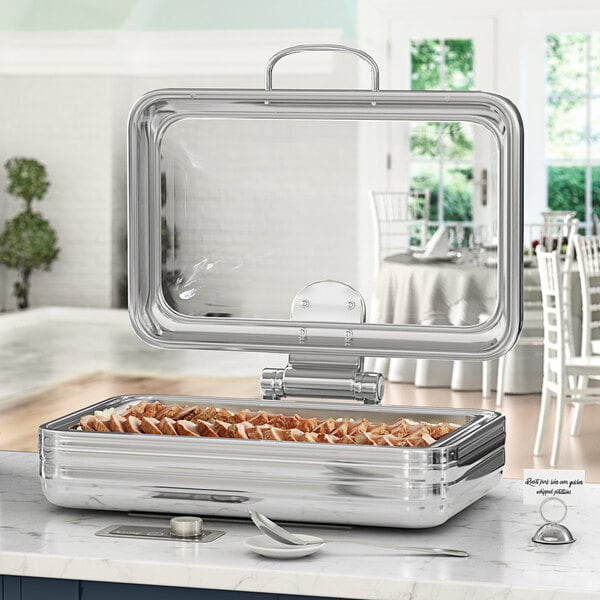 An Acopa stainless steel chafing dish on a counter with food in it.