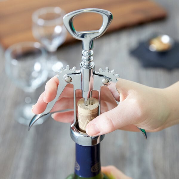 Person uncorking a wine bottle with a wing corkscrew