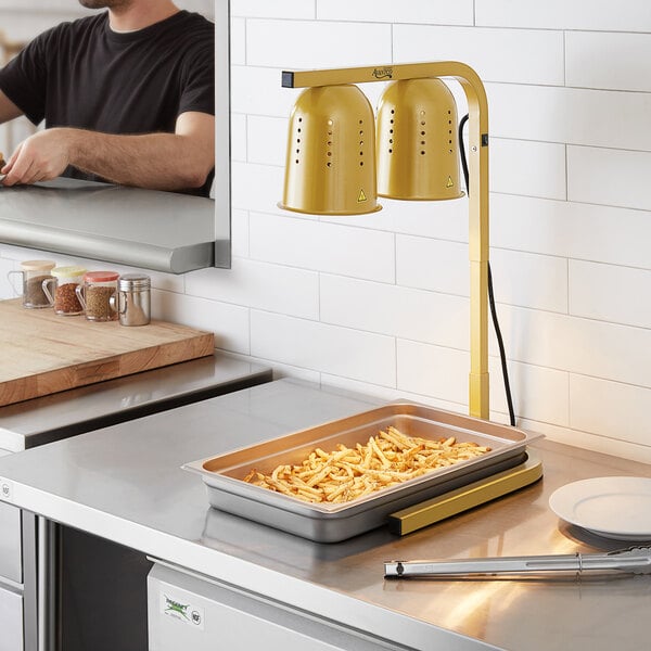 A man using an Avantco countertop heat lamp to cook food in a professional kitchen.