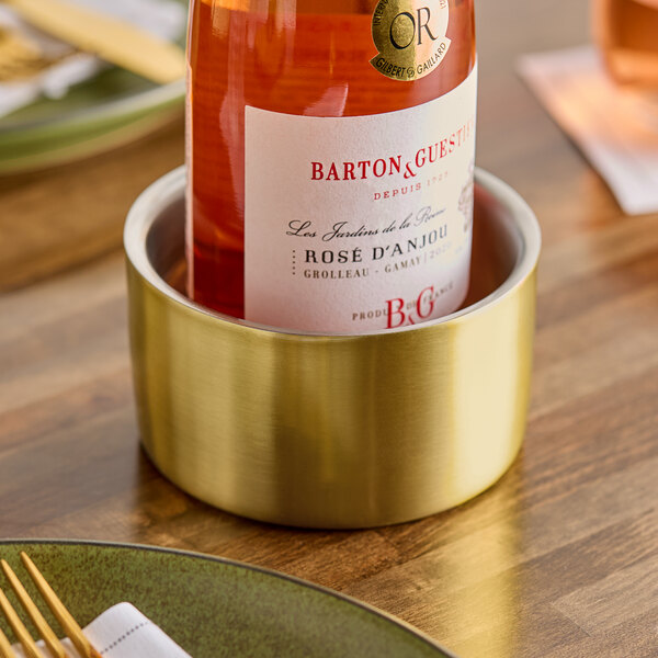 A gold double wall insulated stainless steel bowl or wine coaster holding a bottle of rosÃ© wine.