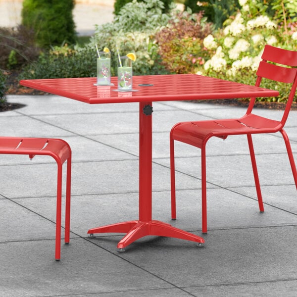 A red Lancaster Table & Seating outdoor table with two chairs.