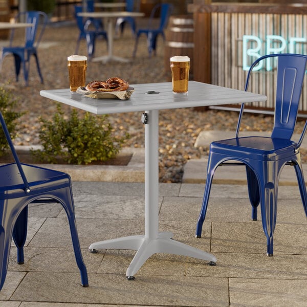 A rectangular silver powder-coated aluminum outdoor dining table with an umbrella hole.
