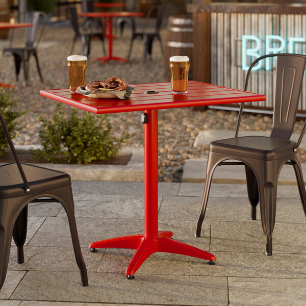 A rectangular red powder-coated aluminum outdoor dining table with an umbrella hole.
