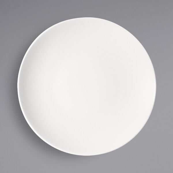 A Bauscher bright white porcelain half-deep coupe plate on a gray surface.