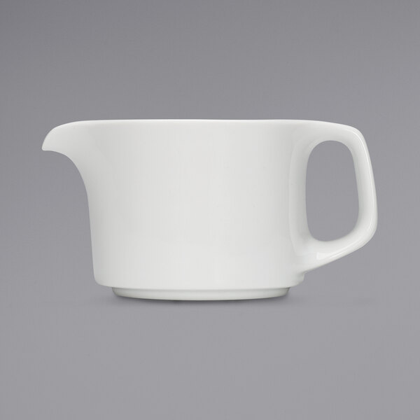 A white teapot with a handle.