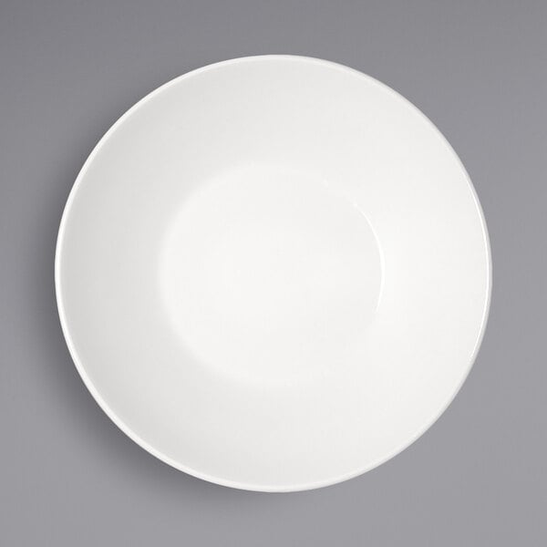 A Bauscher bright white porcelain deep coupe plate with a white rim on a gray background.