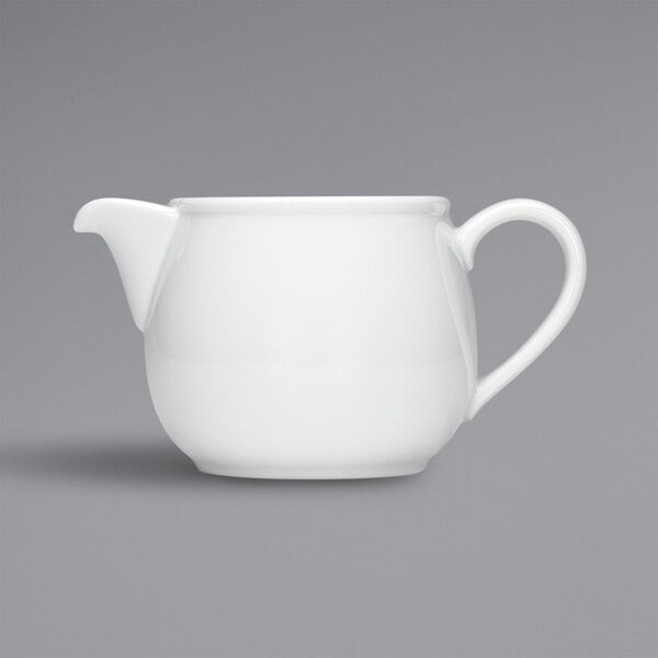 A white teapot with a handle.