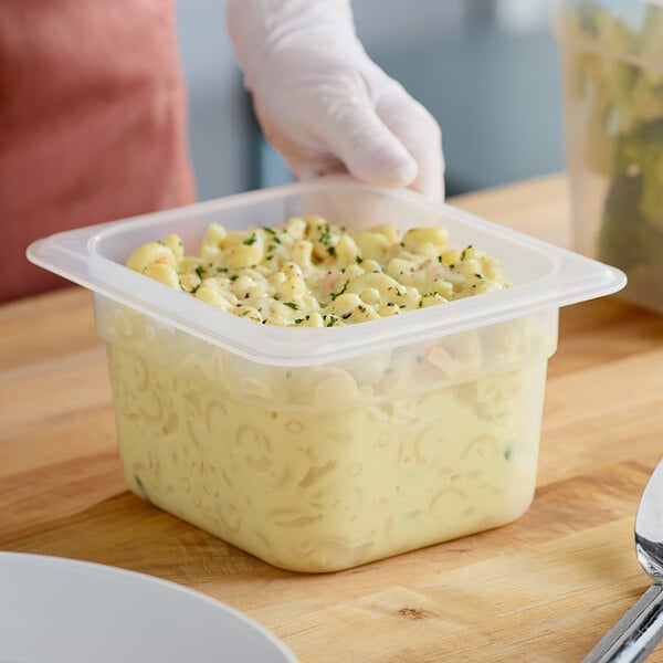 A person holding a Cambro translucent polypropylene food container filled with pasta salad.