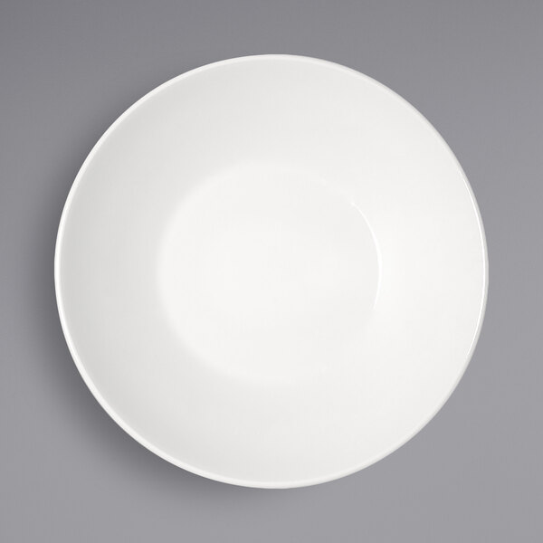 A Bauscher bright white porcelain deep coupe plate with a white rim on a gray surface.