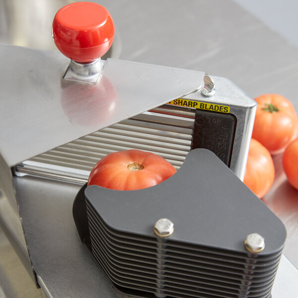 A Vollrath tomato slicer with a 3/16" straight blade assembly slicing a tomato.