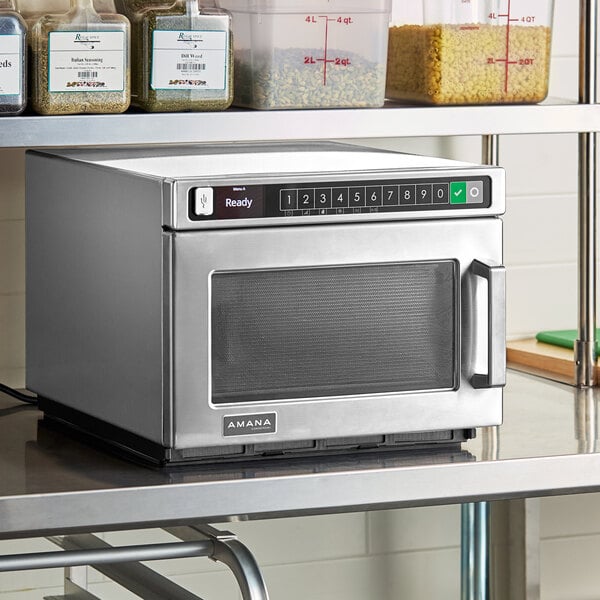 An Amana stainless steel commercial microwave on a counter.