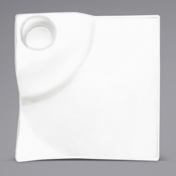 A white square porcelain plate with a well in the middle.