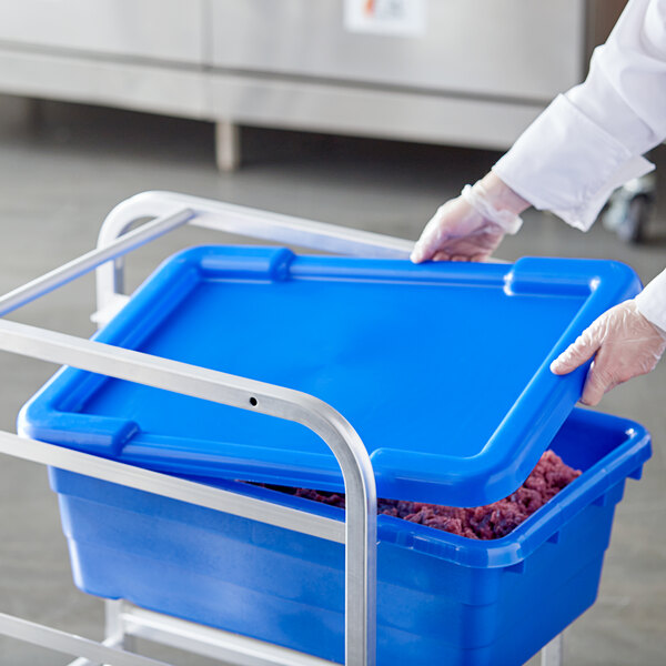 A person in white gloves holding a blue Choice lid for a meat lug.