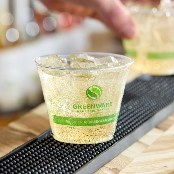 A clear 9 oz. compostable plastic cold cup filled with ice and a light-colored beverage, featuring the Greenware logo and branding.