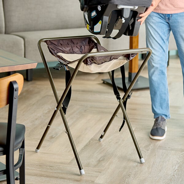 A brown assembled infant seat cradle with a metal frame and fabric seat, designed to hold an infant car seat.