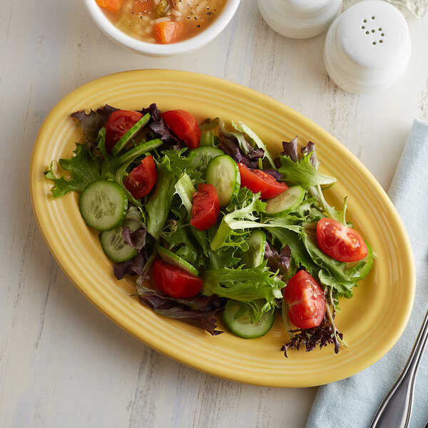 A Tuxton saffron oval china platter with salad and soup on it.