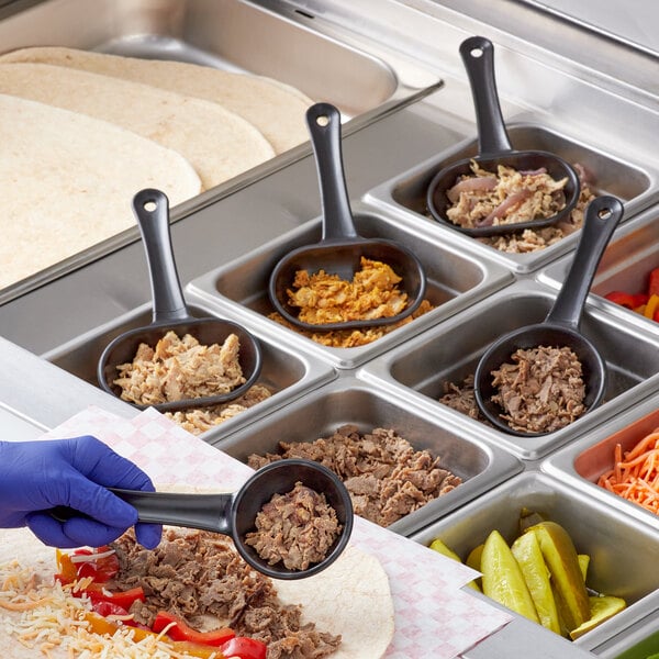 A person using a Nemco black portion control scoop to serve food.