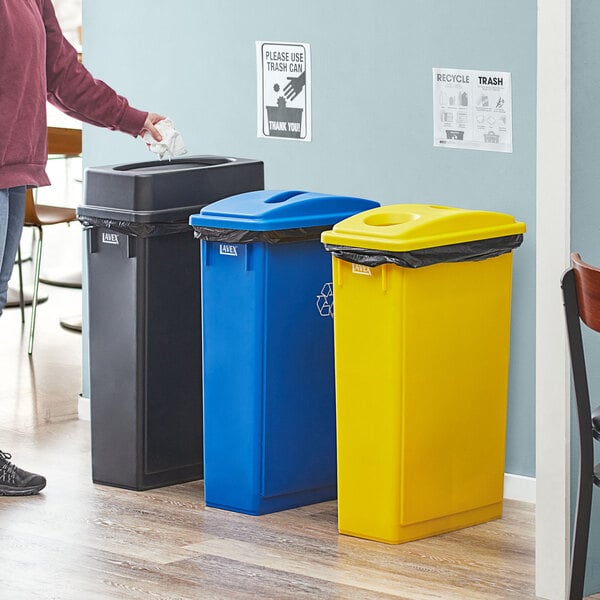 A man standing next to a Lavex 3-stream recycle station with blue and yellow trash cans.