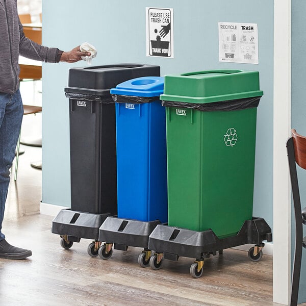 A man standing next to a Lavex 3-stream recycle station with black, green, and blue lids.