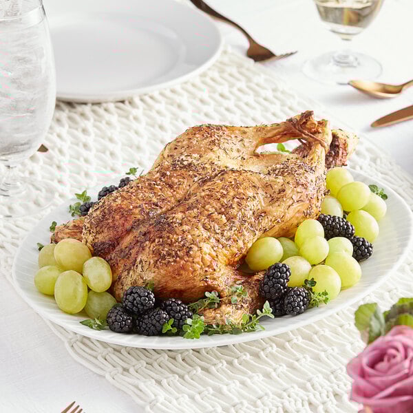 a whole chicken with grapes and berries on a plate