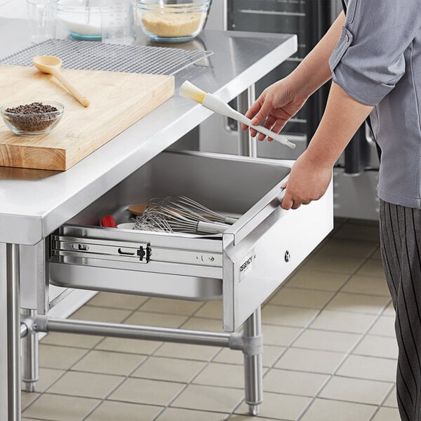 A person opening a Regency stainless steel drawer with locks.