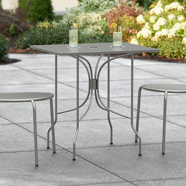 A Lancaster Table & Seating Harbor Gray rectangular outdoor table with two chairs on a patio.