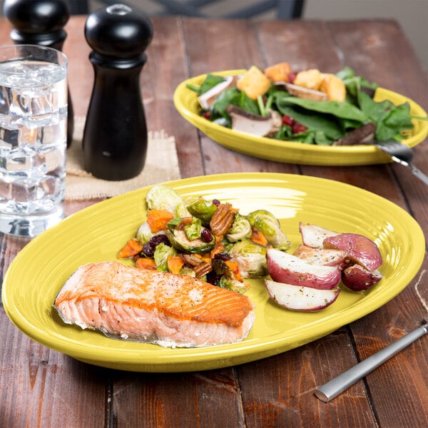 A Fiesta china platter with a salad and salmon on a table.