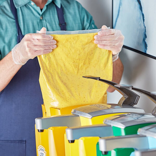 A man in a blue shirt holding a yellow Heinz Honey Mustard bag.