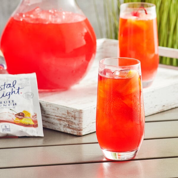 a glass of red liquid with ice and orange liquid